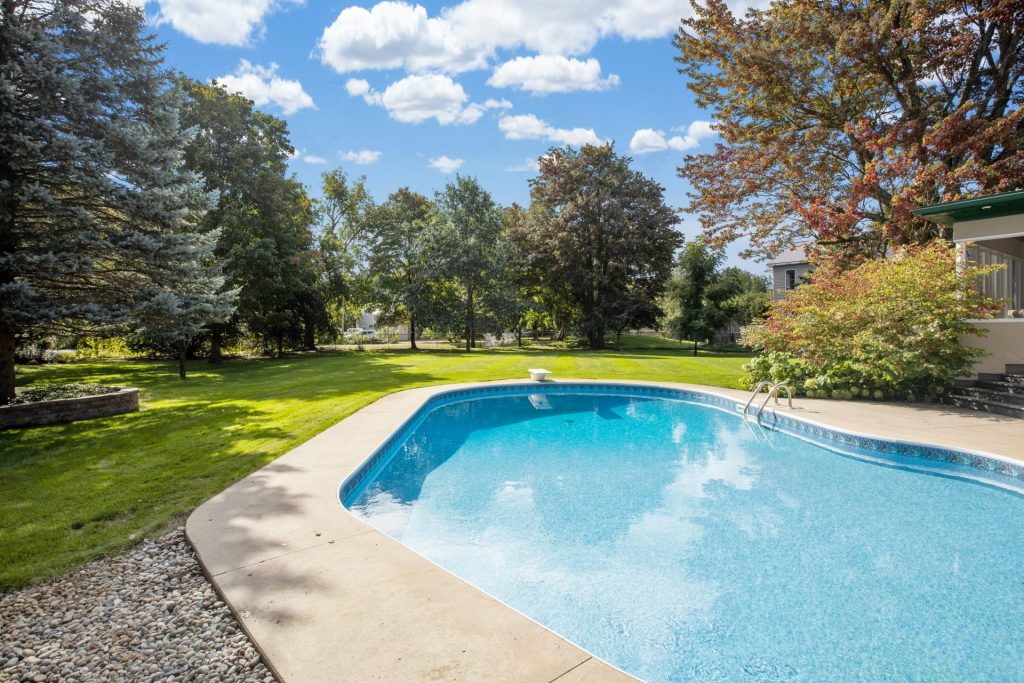 a large swimming pool in a backyard surrounded by trees