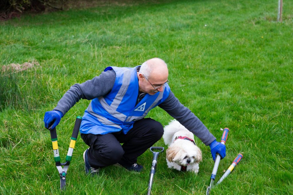 Gardener with tools and small dog on grass