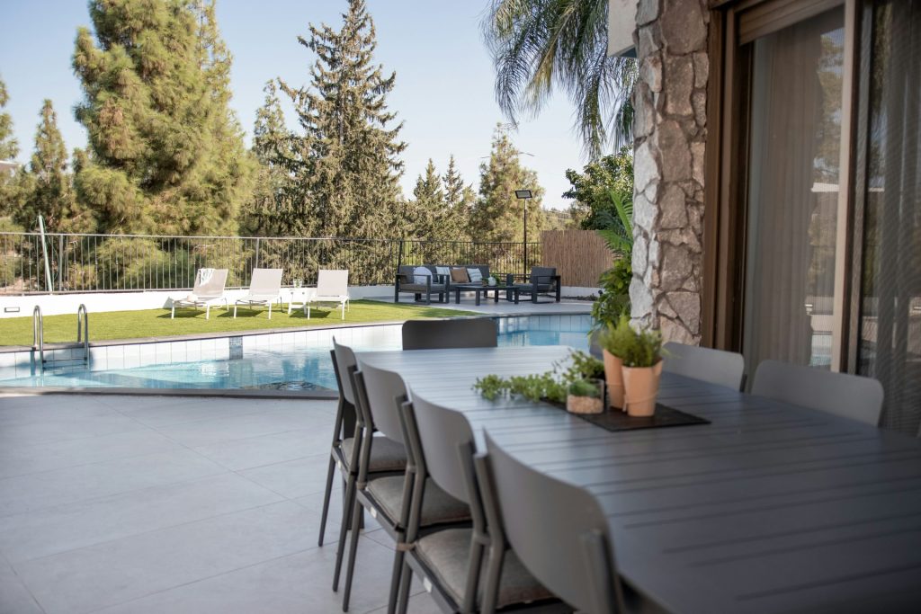 Outdoor dining table and chairs by a swimming pool.